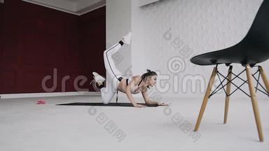 年轻的金发女人在她的肘部做瑜伽姿势的运动。 健身训练。 健身。 地板上的印子是白色的